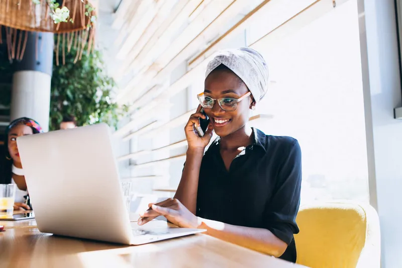 Femme d'affaires africaine utilisant son téléphone mobile — site web bilingue français anglais accessible sur mobile pour les marchés anglophones