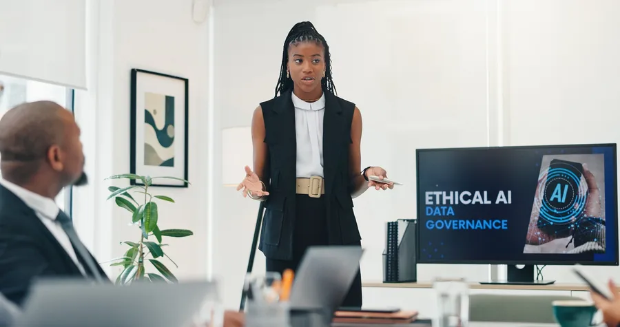 Boardroom meeting with a business woman presenting on screen during an ethical AI and data governance discussion