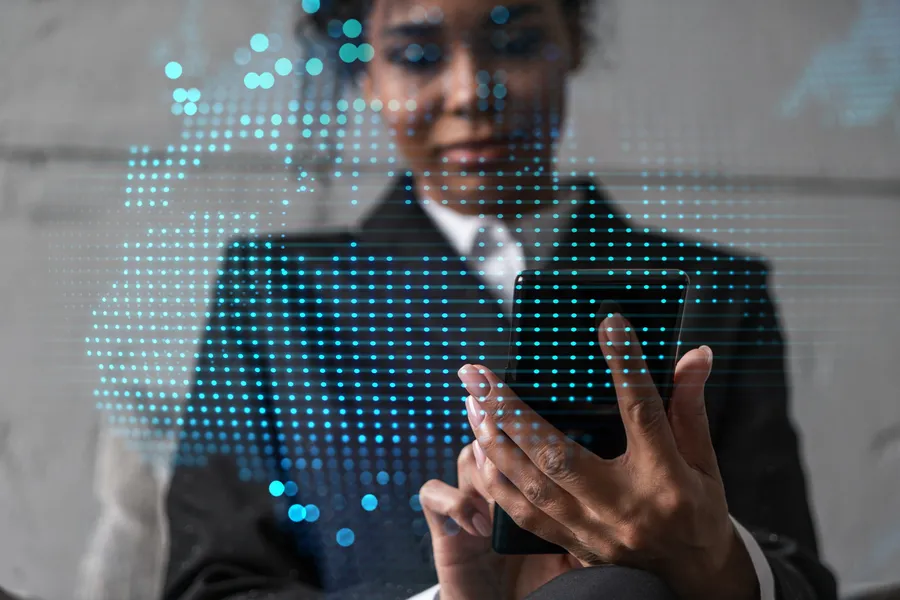 Business woman using a phone in a modern office with a world-map hologram — building an AI strategy around a real business problem