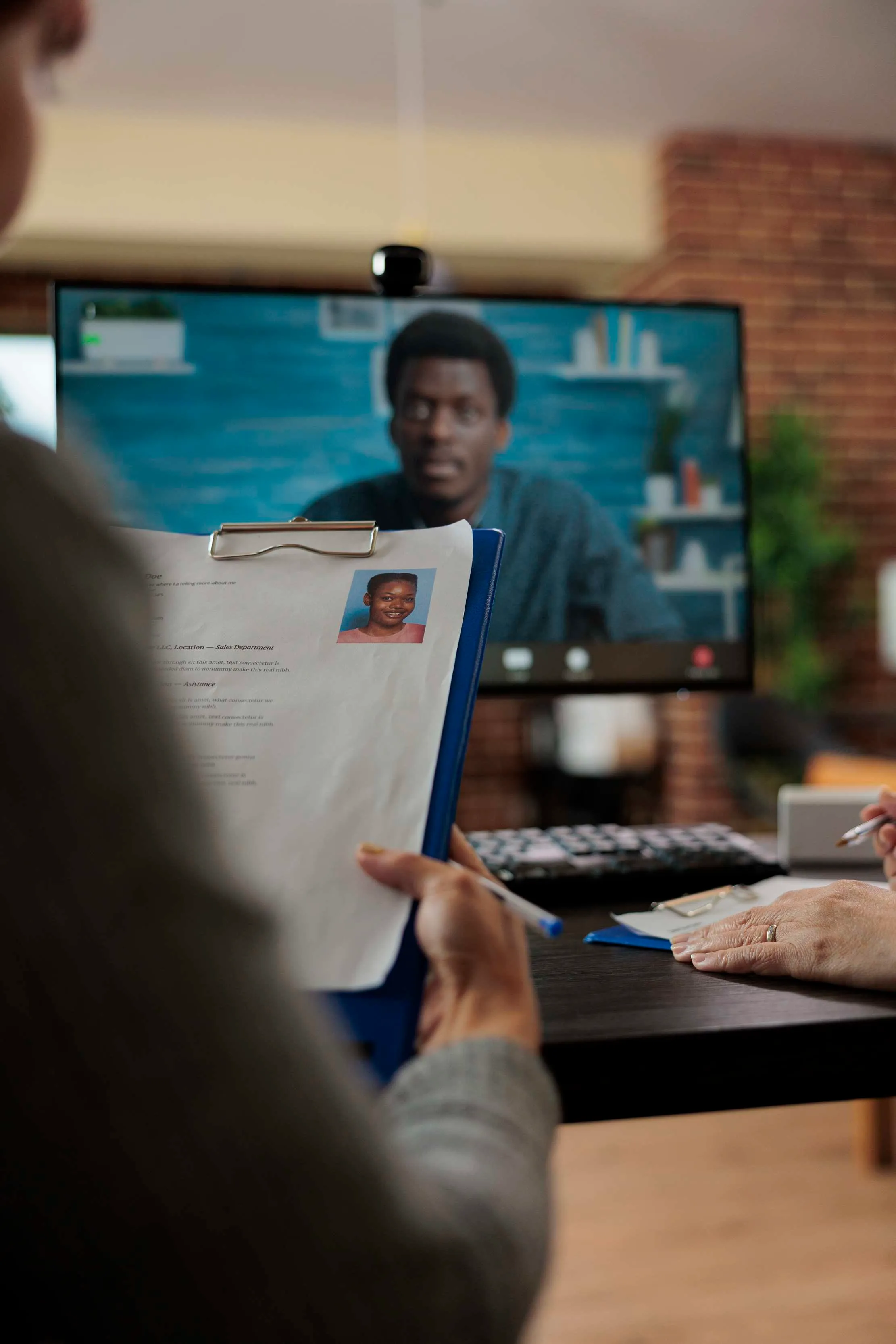 Recruitment candidate holding a CV beside a digital device, representing human review of an AI-assisted hiring process