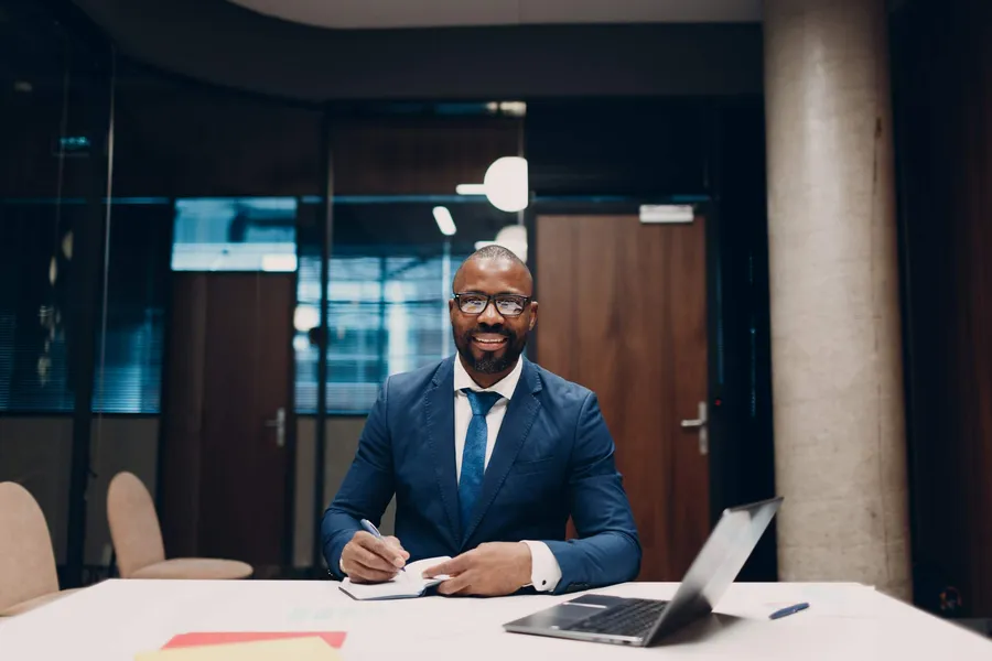 Dirigeant africain prenant des notes lors d'une session de stratégie IA avec ordinateur portable et carnet