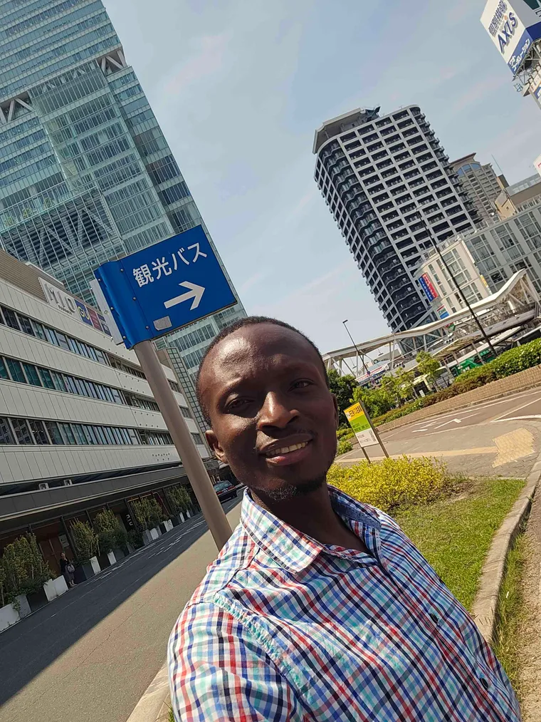 Peter Bamuhigire devant une station de transport en ville