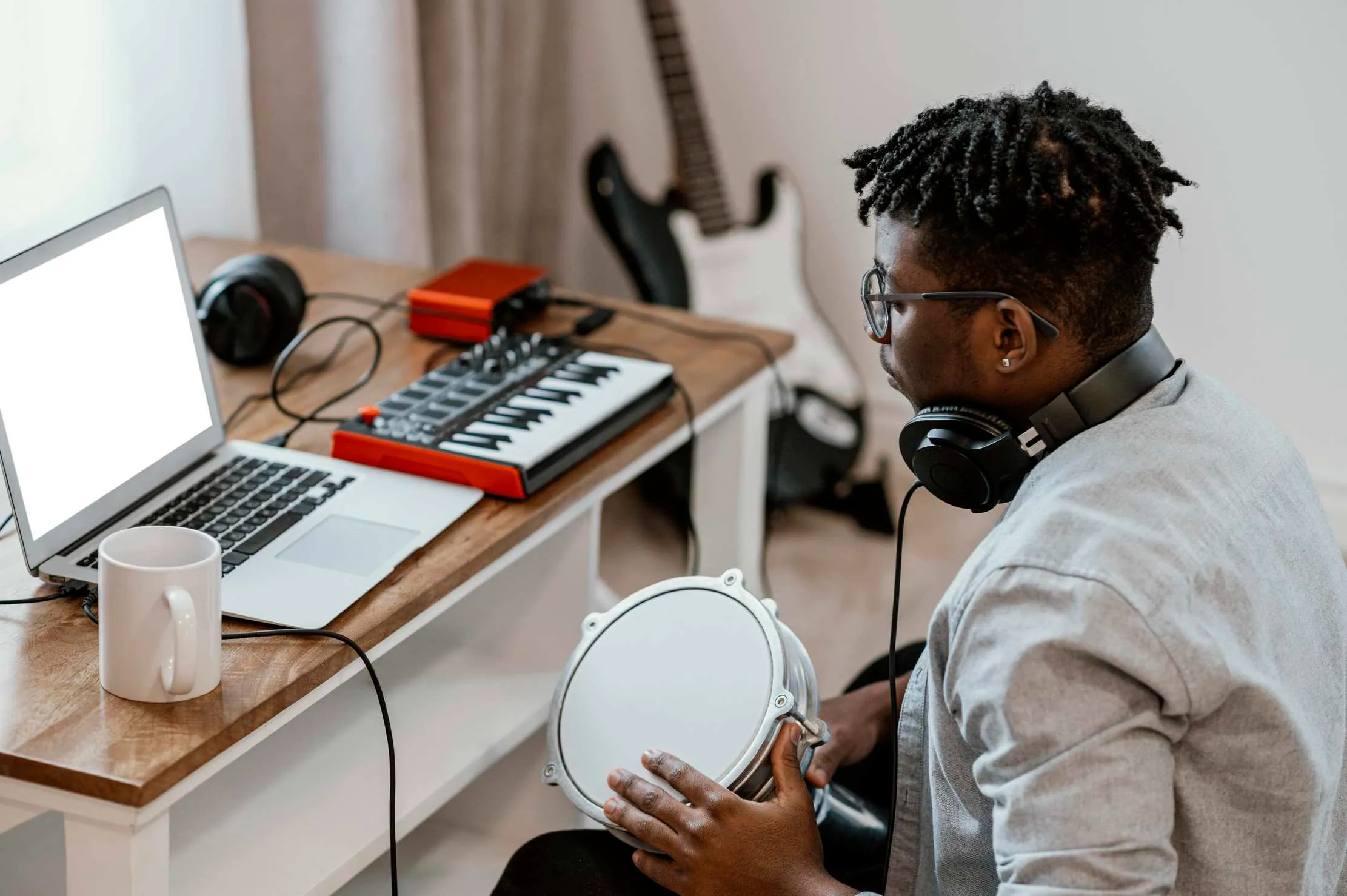 Musicien jouant batterie et mixant avec laptop — studio maison production musicale Ouganda Afrique