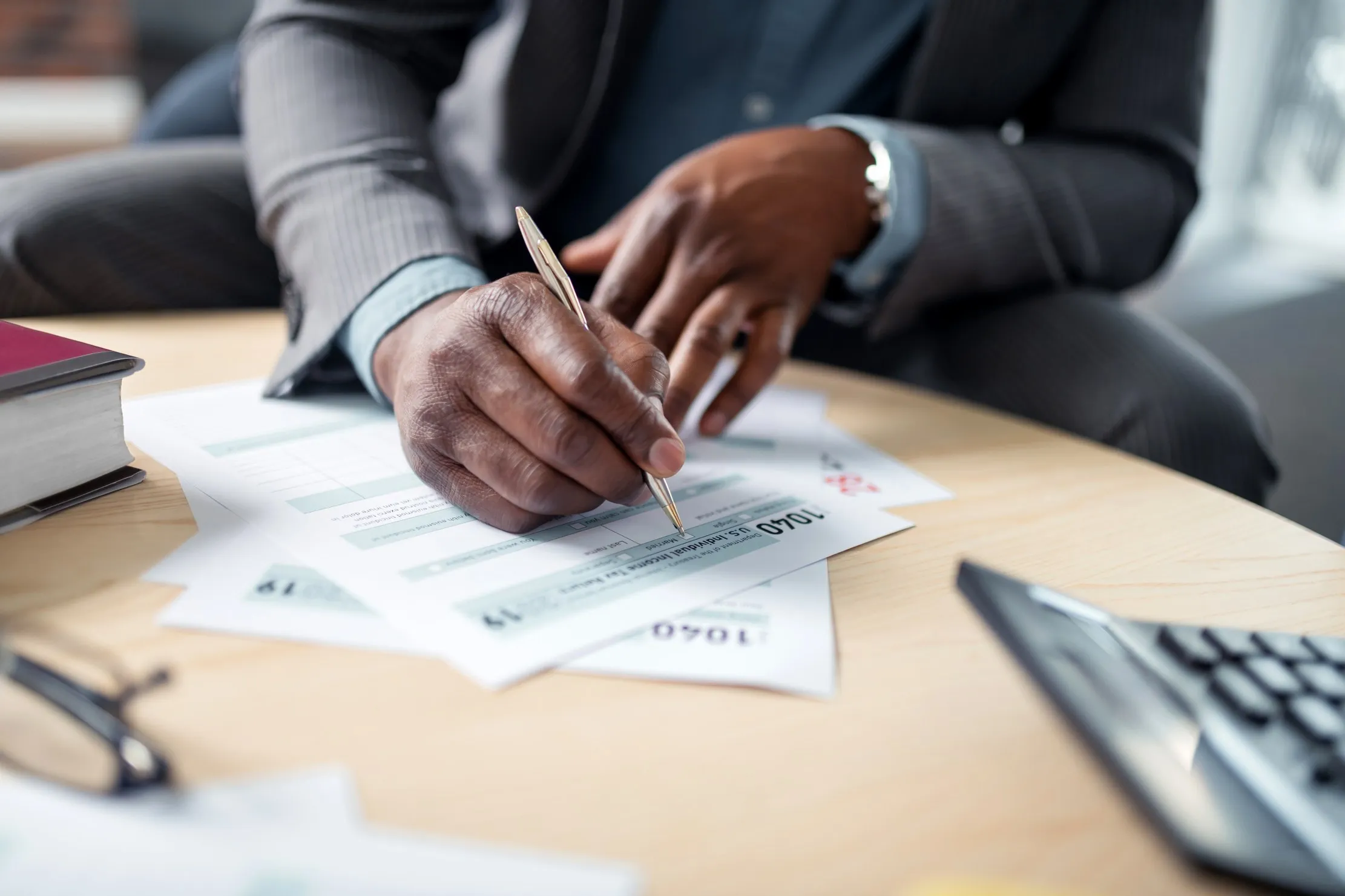 Business professional signing documents and reviewing financial evidence at a desk