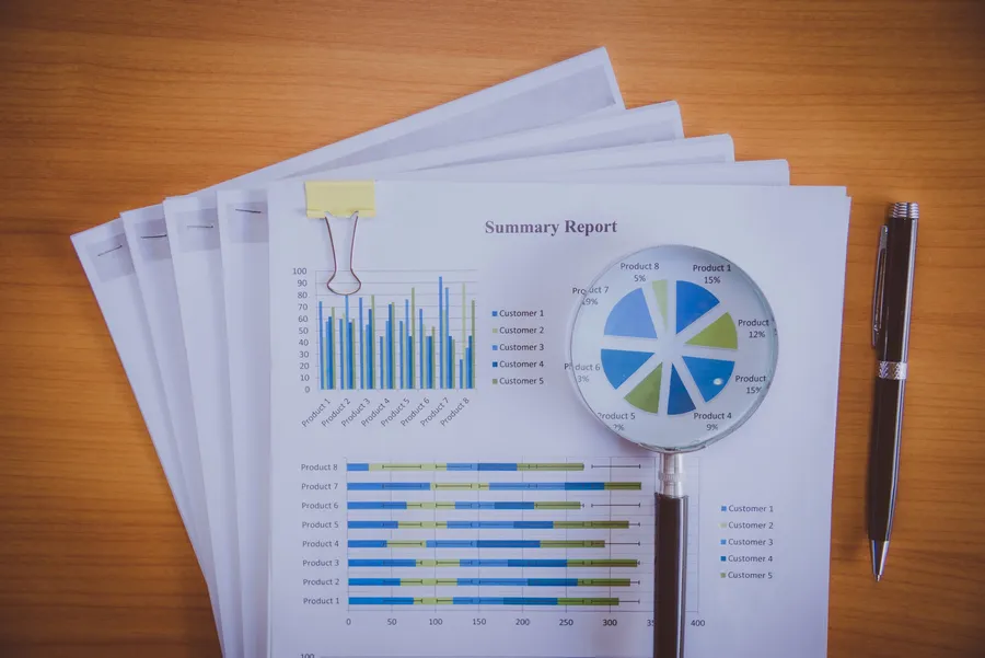 Loupe examinant un graphique imprimé, illustrant un reviseur remontant un chiffre jusqu'à sa source