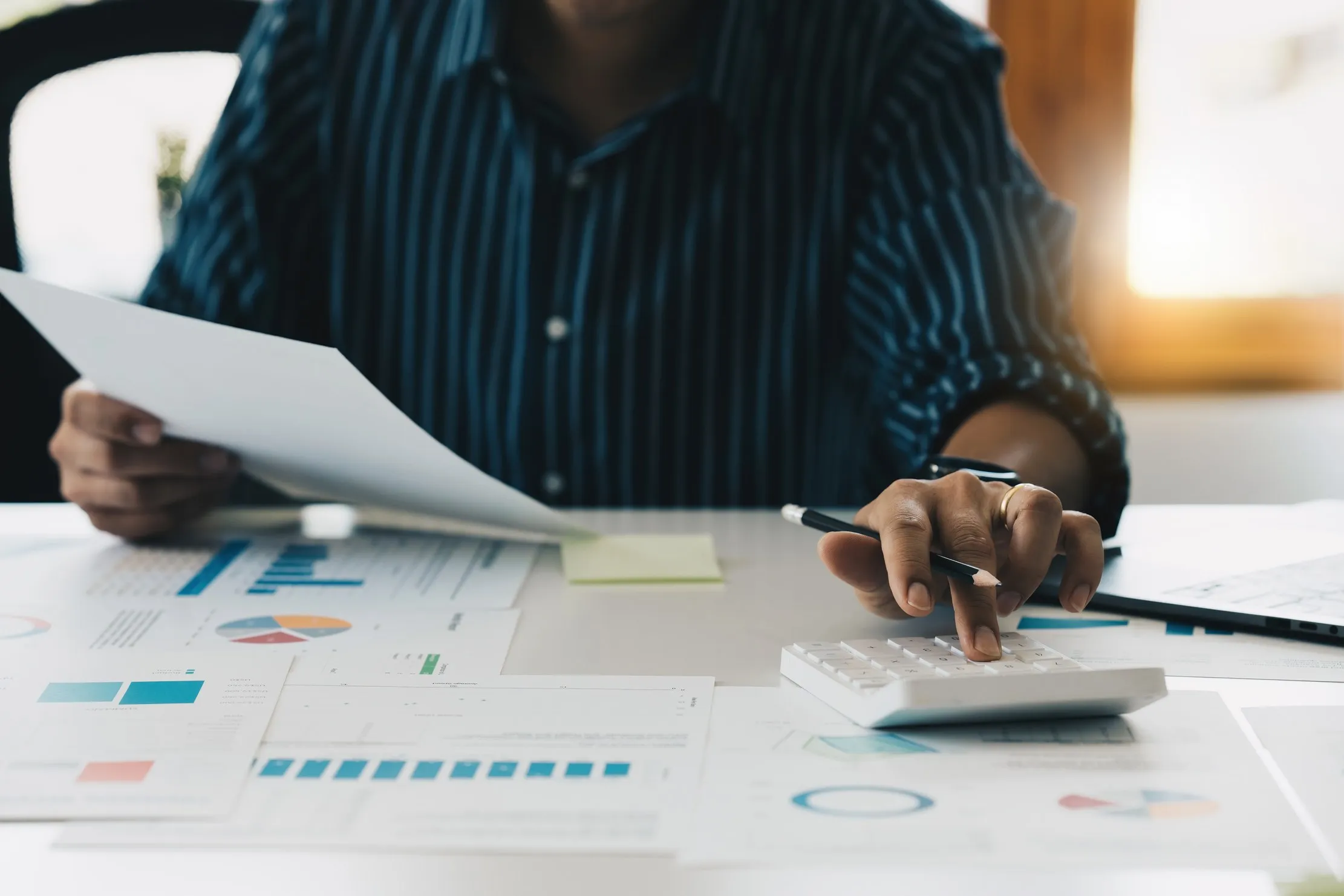 Responsable financier vérifiant des chiffres avec une calculatrice et des pièces justificatives, illustrant un reporting prêt pour l'audit