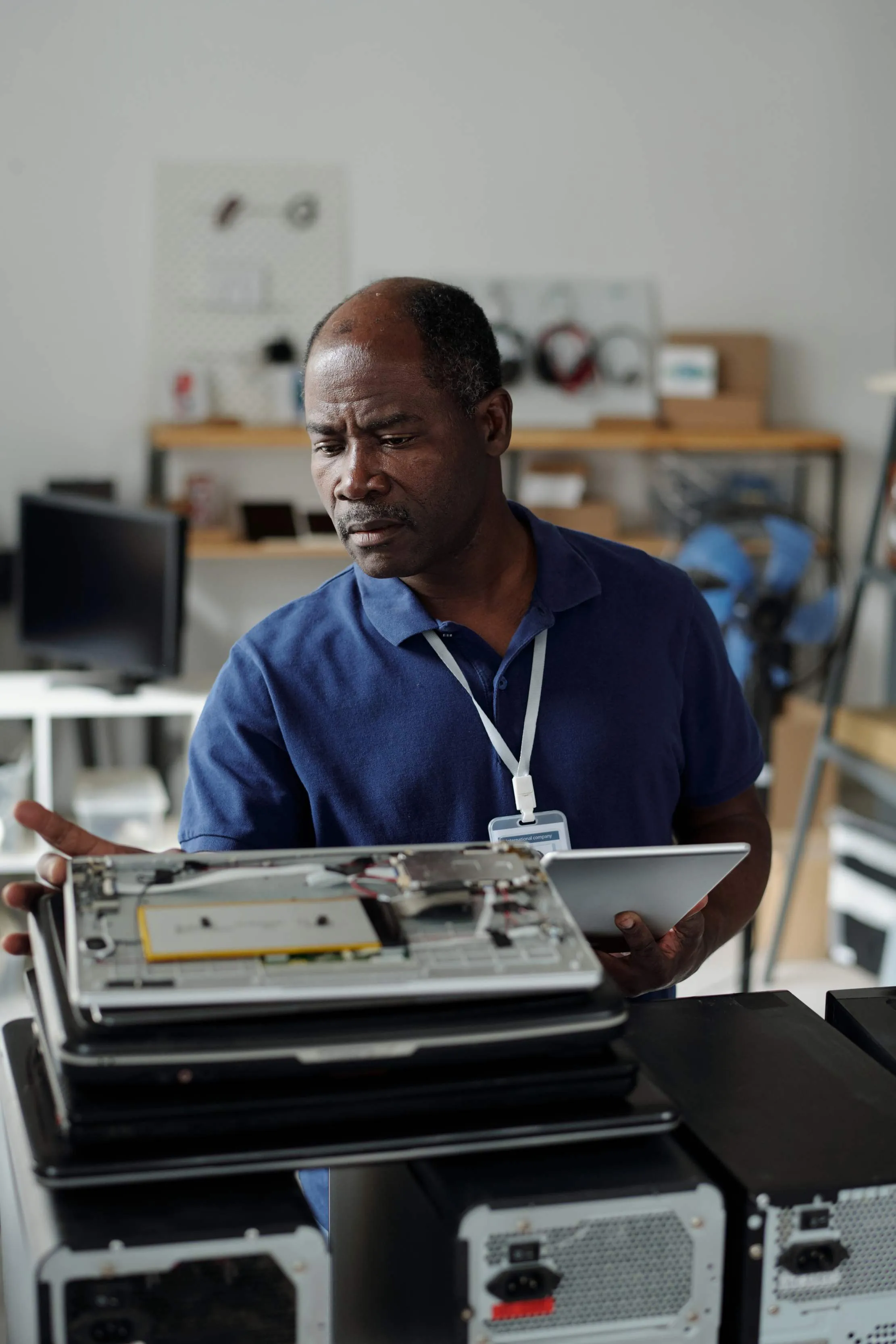 Technician inspecting an opened piece of equipment while holding a tablet in a repair workshop